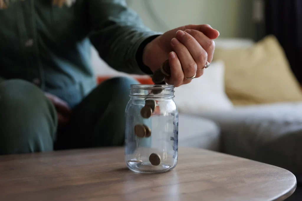 Individual inserting cash into a jar for zero-based budgeting illustration